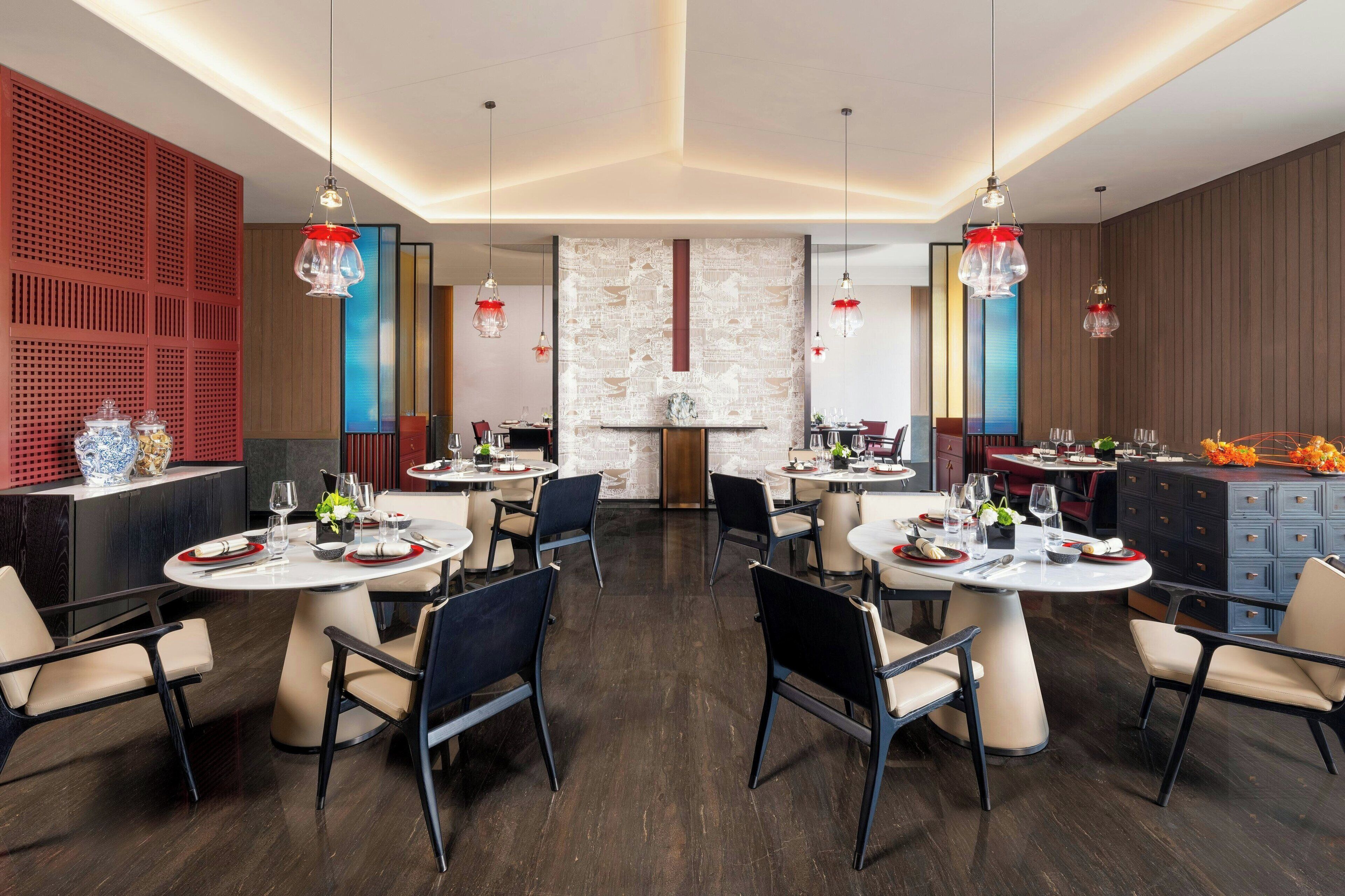 A modern dining area with round tables, chairs, and pendant lighting.