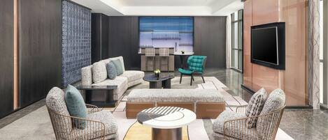 A modern living room with a sectional sofa, two armchairs, a coffee table, and a TV mounted on a wooden cabinet.