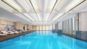 Une grande piscine intérieure au design moderne, caractérisée par une forme longue et rectiligne et une eau d’un bleu limpide.