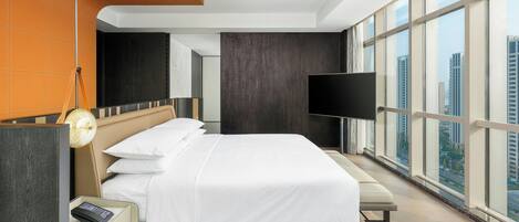 Una camera d'albergo moderna con un letto grande, una televisione a schermo piatto e vista sulla città da ampie finestre.