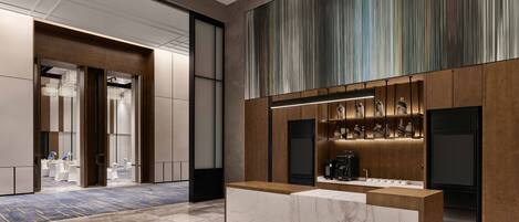 Un hall d’hôtel moderne avec un comptoir d’accueil, un grand mur à rayures et un espace salon comprenant des tables et des chaises.