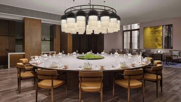 A modern conference room with a round table, chairs, and a chandelier.