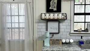 Una cocina con armarios blancos, una cafetera y un letrero que dice 'Mississippi My Home Sweet Home'.