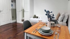 Une table à manger dressée avec des assiettes, des bols et des couverts, un vase rempli de fleurs et un verre de vin.
