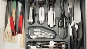 Un tiroir contenant divers ustensiles de cuisine, notamment des cuillères, une spatule et une pince.