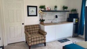 A small kitchen with a plaid armchair, a sink, and a microwave. - Elenem Resort (Magalang)
