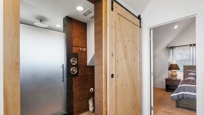 Une chambre avec une porte coulissante, un lit, une table de chevet, une lampe et une fenêtre avec des stores.