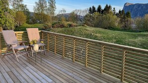 A wooden deck with two striped chairs and a small table with a vase of flowers. - Lovely home in Sørbøvåg (Sørbøvåg)