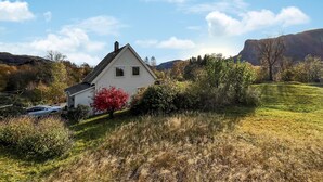 A white house with a gabled roof, surrounded by a grassy landscape and trees. - Lovely home in Sørbøvåg (Sørbøvåg)