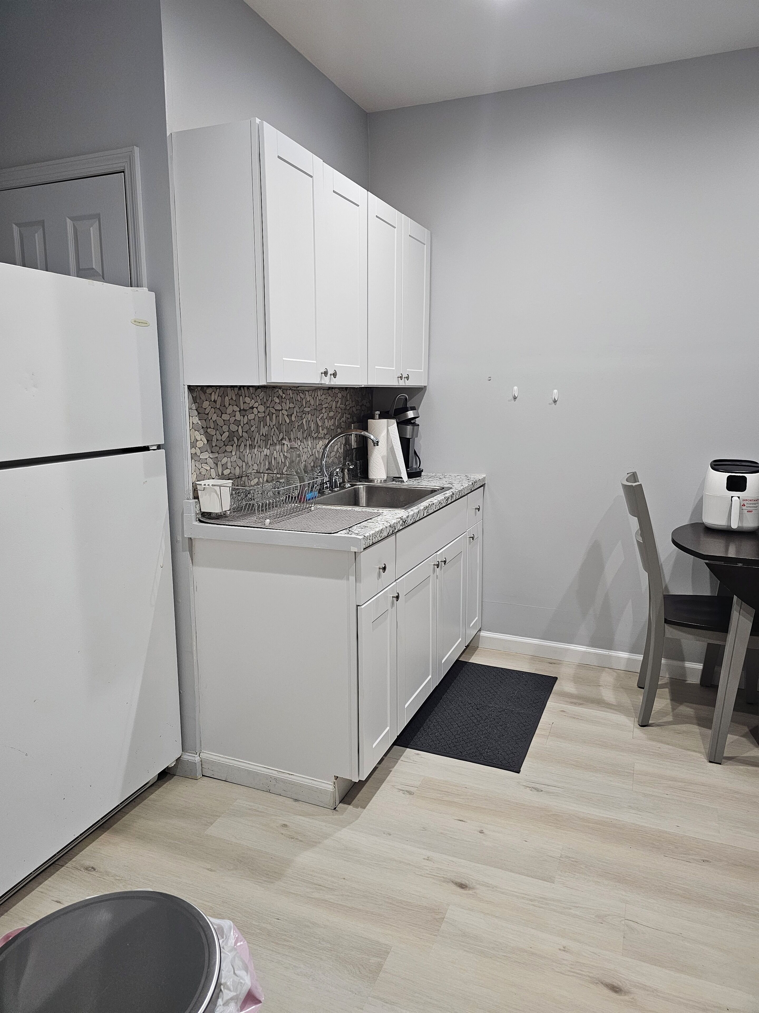 A compact kitchen with white cabinets, a stainless steel sink, and a coffee maker.