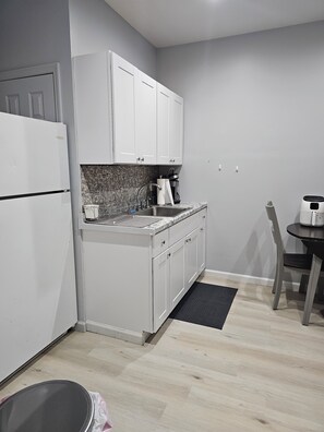 A compact kitchen with white cabinets, a stainless steel sink, and a coffee maker.