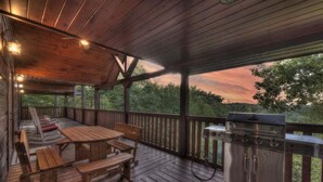 A covered outdoor deck with wooden furniture and a grill. - Black Bear Hollow - Gather, Play, Relax, Repeat (Blue Ridge)
