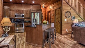 A cabin interior with a kitchen, dining area, and a living room. - Black Bear Hollow - Gather, Play, Relax, Repeat (Blue Ridge)