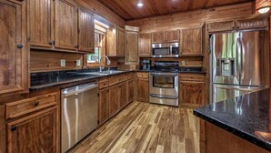 A kitchen with wooden cabinets, stainless steel appliances, and a granite countertop. - Black Bear Hollow - Gather, Play, Relax, Repeat (Blue Ridge)