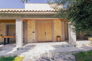 Un edificio de piedra con una puerta de madera, un banco y una planta en maceta.