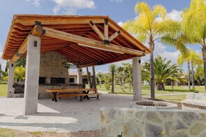 Un espacio al aire libre techado con un banco de piedra y una chimenea.