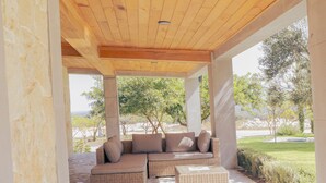 An outdoor covered patio with a wooden ceiling, stone flooring, and a seating area with a sofa and cushions. - Vid de Luna (San Miguel de Allende)