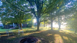 Ein Garten mit einem Kamin aus Ziegelsteinen, einer Rasenfläche und einem Haus im Hintergrund.