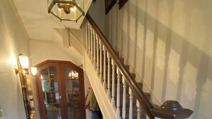 Ein Flur mit Fliesenboden, einer Treppe mit weißen Spindeln und einer Tür mit Glasfeldern.
