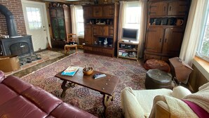 Ein gemütliches Wohnzimmer mit Kamin, Holzschränken, einem Fernseher und einer komfortablen Sitzecke.