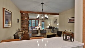 A spacious kitchen with a marble countertop, a brick fireplace, and a dining area with a chandelier.