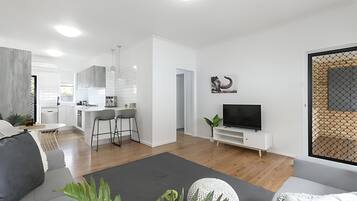Un espacio habitable moderno con cocina, comedor y una zona de estar con televisor.