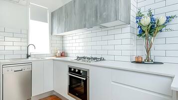 Una cocina moderna con armarios blancos, horno integrado y estufa a gas.