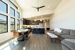 Ampla sala de estar com mesa de jantar, cadeiras, sofá e cozinha com balcão.