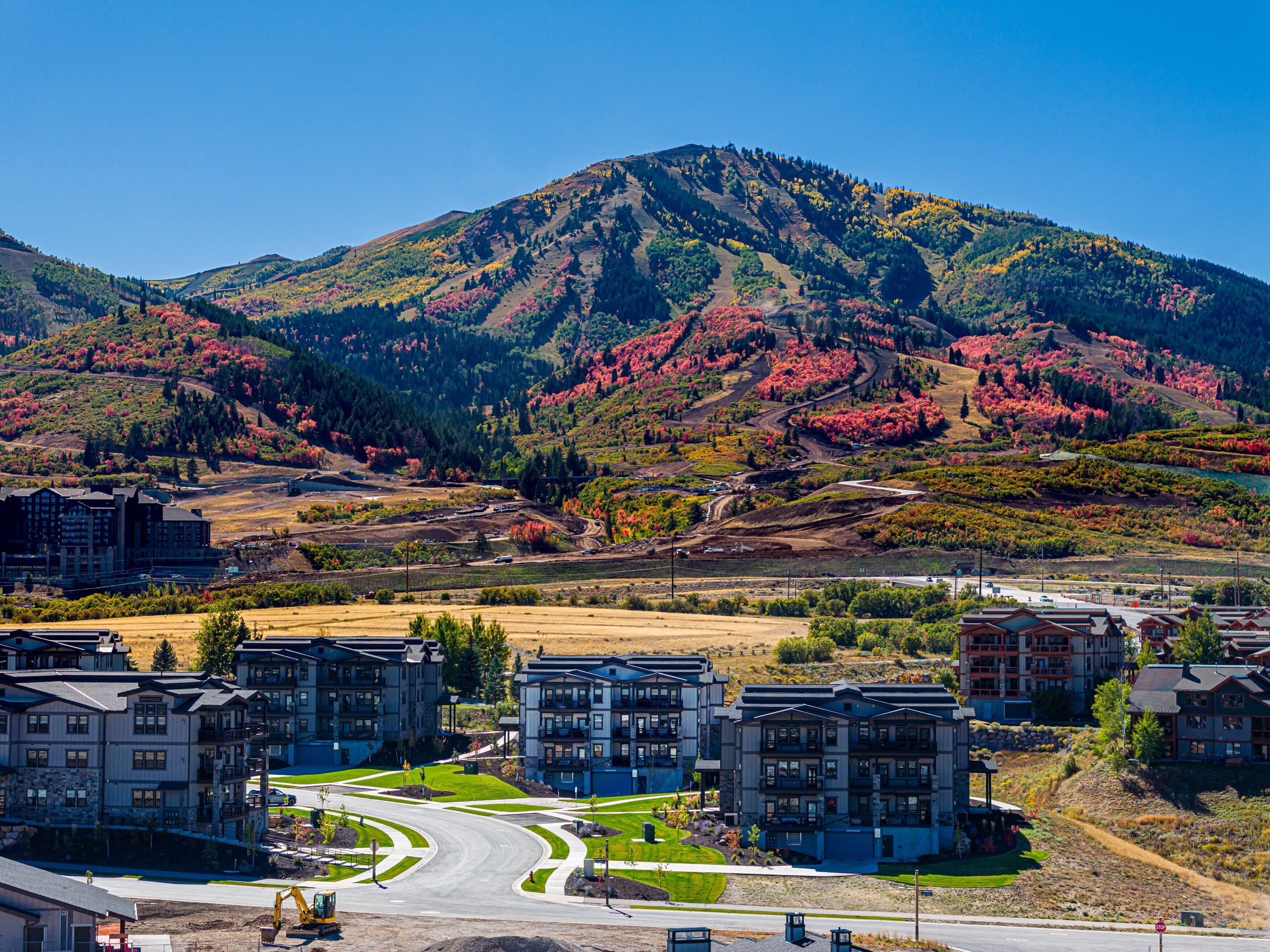 A residential area with modern apartment buildings, a winding road, and a mountain in the background.