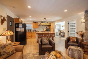 A modern kitchen with a central island, wooden cabinets, and a dining area with chairs.