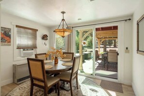 A dining area with a table, chairs, a chandelier, and a view through a glass door to an outdoor patio.