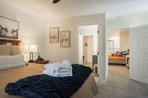 A hotel room with a bed, a nightstand, a lamp, and a painting on the wall.