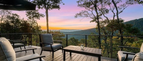 Une terrasse avec des sièges extérieurs, une table en verre et une vue sur le paysage.