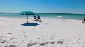 A beach with a single umbrella and two chairs.