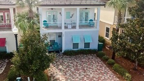 A two-story house with a balcony, a covered porch, and a brick driveway.