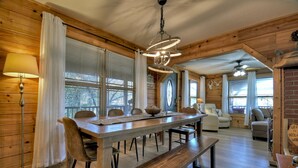 A wooden interior with a dining table, chairs, a bench, and a chandelier. - Moon Tower Cabin - Beautiful Water Views, Firepit + More! (Blairsville)