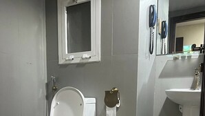 Et moderne badeværelse med toilet, vask og spejl.