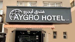 Aygro Hotel LLC, med et skilt på både arabisk og engelsk, en trappeopgang til indgangen og en brobelagt forplads foran.