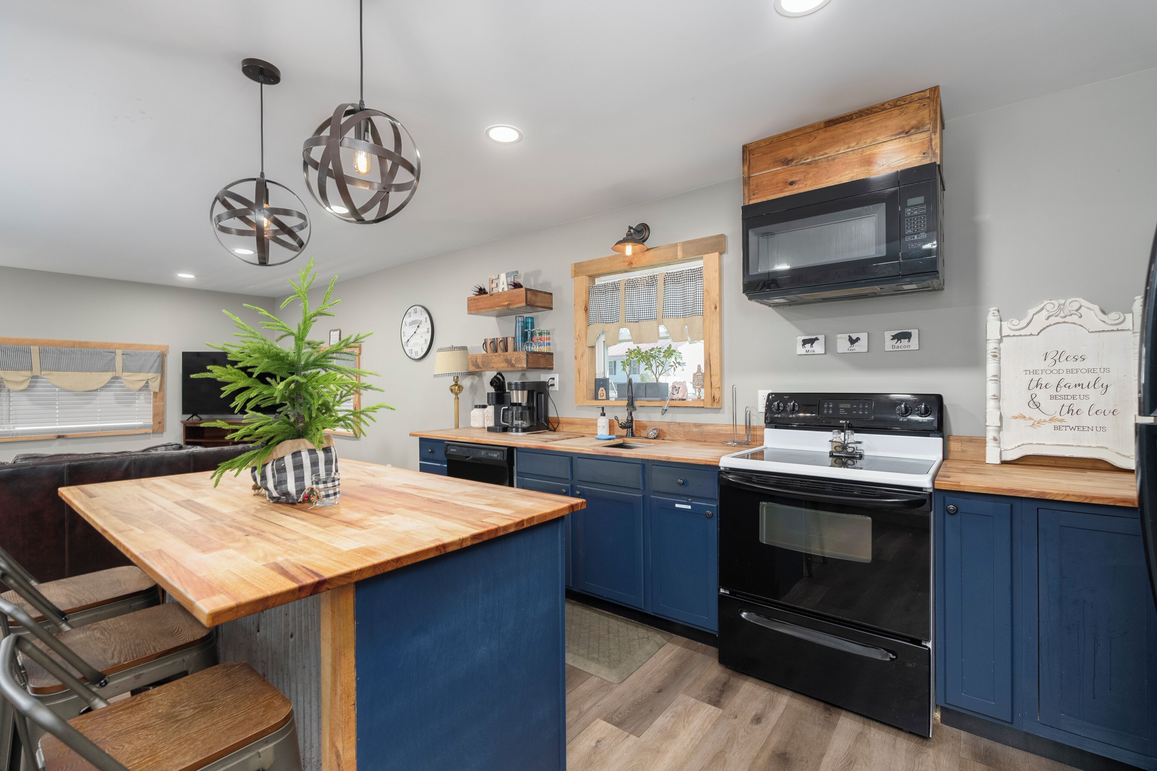 Une cuisine moderne avec des armoires bleues, un îlot central en bois et une cuisinière noire.