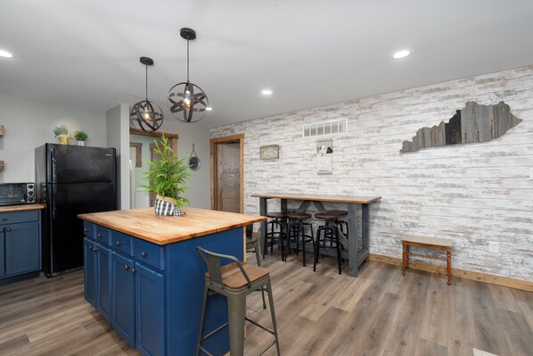 Una cocina moderna con armarios azules, una isla de madera y taburetes de bar.