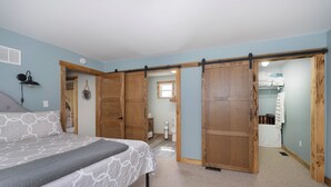 Ein Schlafzimmer mit Bett, Holzschiebetüren, einem Schminktisch und einem kleinen Fenster.