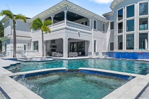 A two-story building with a swimming pool, outdoor seating, and a covered patio area.
