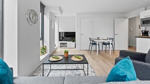 A modern living room with a sofa, a coffee table, and a dining area with chairs and a table. - VICHY - Baltic Triangle Modern Apartment (Liverpool)