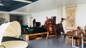 Un salón moderno con una gran escultura de madera, sofás verdes y una mesa de comedor.