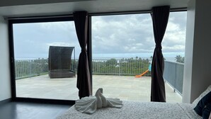 Una habitación de hotel con una cama, un balcón y vistas al mar, y una silla.