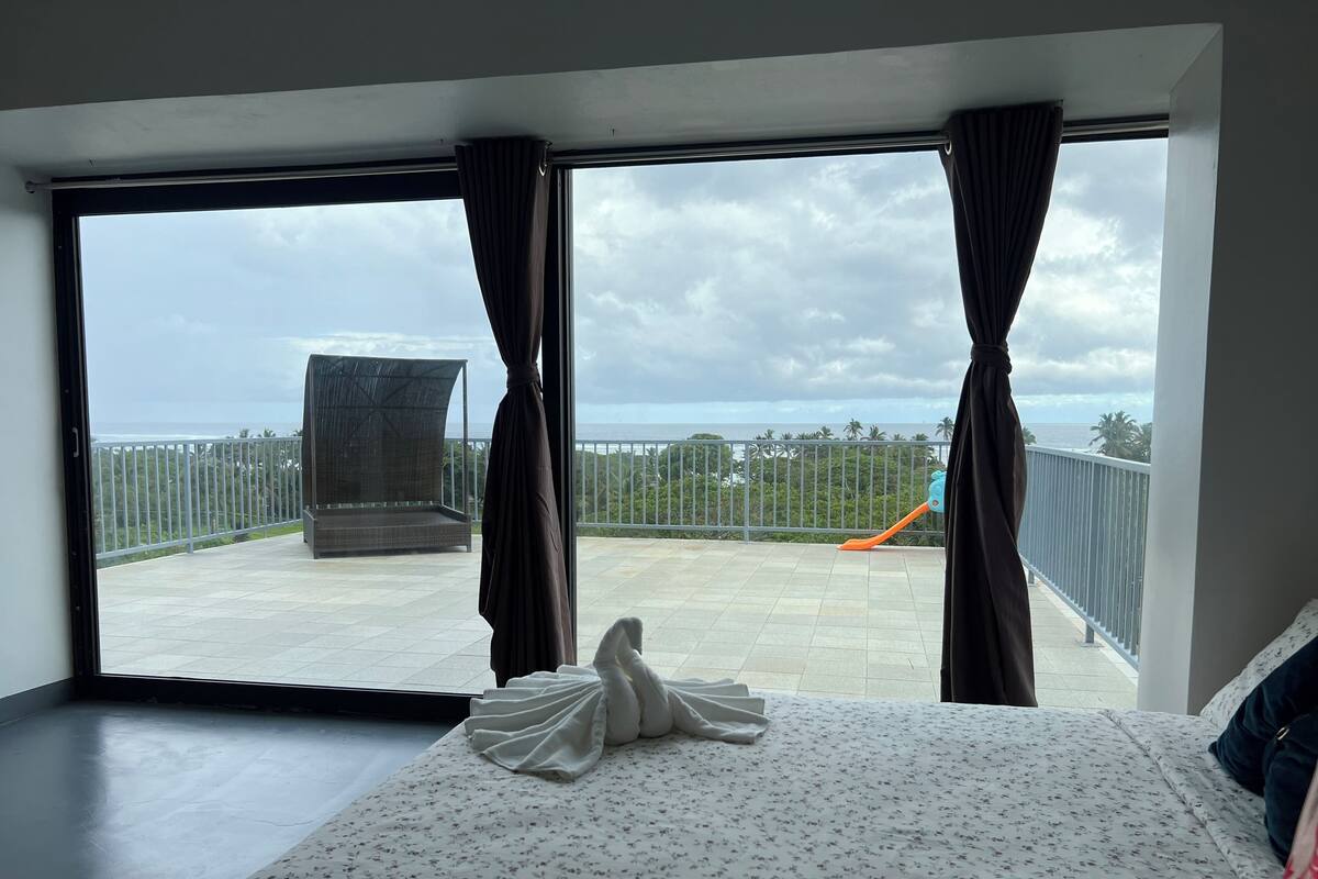 Habitació d'hotel amb un llit, un balcó que dona al mar i una cadira.