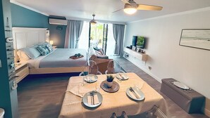 Un dormitorio con cama, mesita de noche y televisor en la pared.