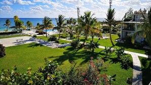 Un resort con zona de piscina, palmeras y vista al océano.