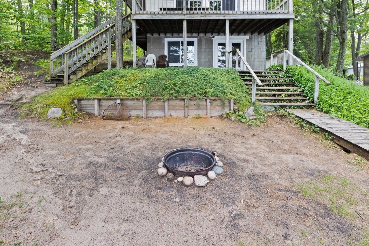 Eine Holzhütte mit einer Holzdar Terrasse, einer Feuerstelle und einer Treppe zum Haupteingang.
