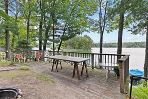 Une terrasse en bois avec une table et des chaises donnant sur un lac.